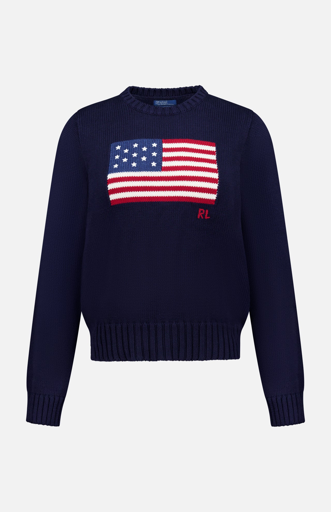 The RALPH LAUREN POLO Roving Cotton Flag Long Sleeve Pullover Sweater features a navy knit design with an American flag on the chest, red RL initials below, and ribbed cuffs, hem, and collar.