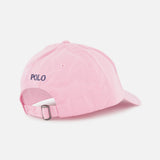 The Twill Logo Cap by RALPH LAUREN POLO is a light pink cotton chino cap with an adjustable strap and metal buckle. "POLO" is embroidered in navy above the opening, while the signature Pony adds a subtle touch. Plain white background.