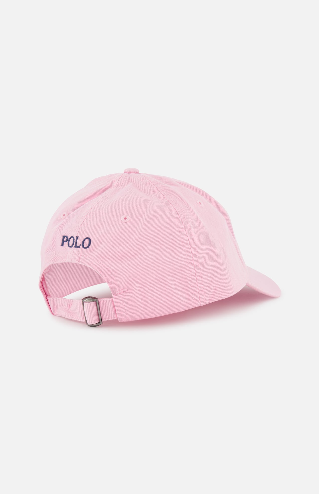 The Twill Logo Cap by RALPH LAUREN POLO is a light pink cotton chino cap with an adjustable strap and metal buckle. "POLO" is embroidered in navy above the opening, while the signature Pony adds a subtle touch. Plain white background.