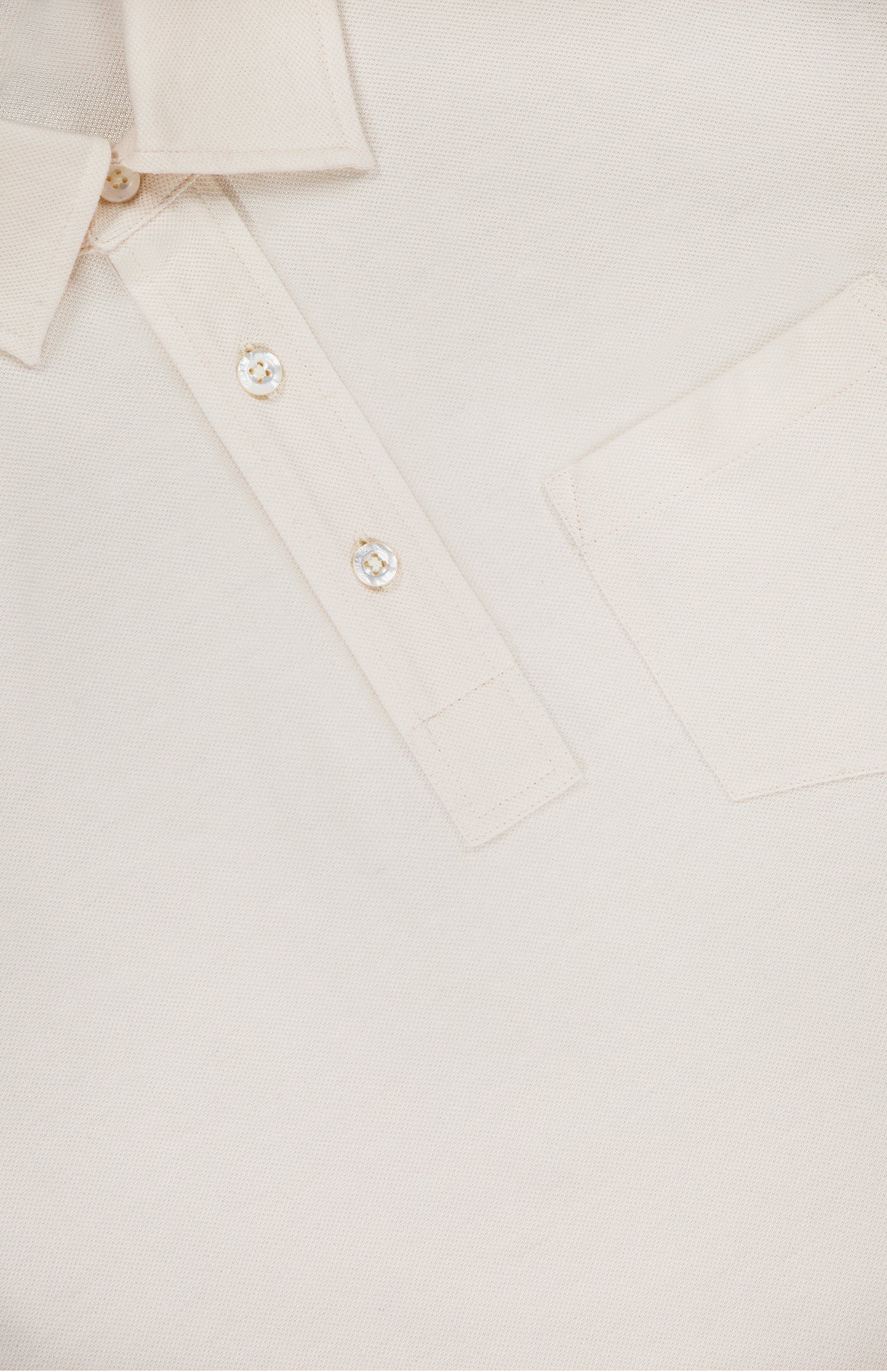 Close-up of the RALPH LAUREN PURPLE LABEL Cotton Cashmere Pique Short Sleeve Polo Shirt in cream, made in Italy, showing the collar, three Mother of Pearl buttons, chest pocket, and textured fabric.