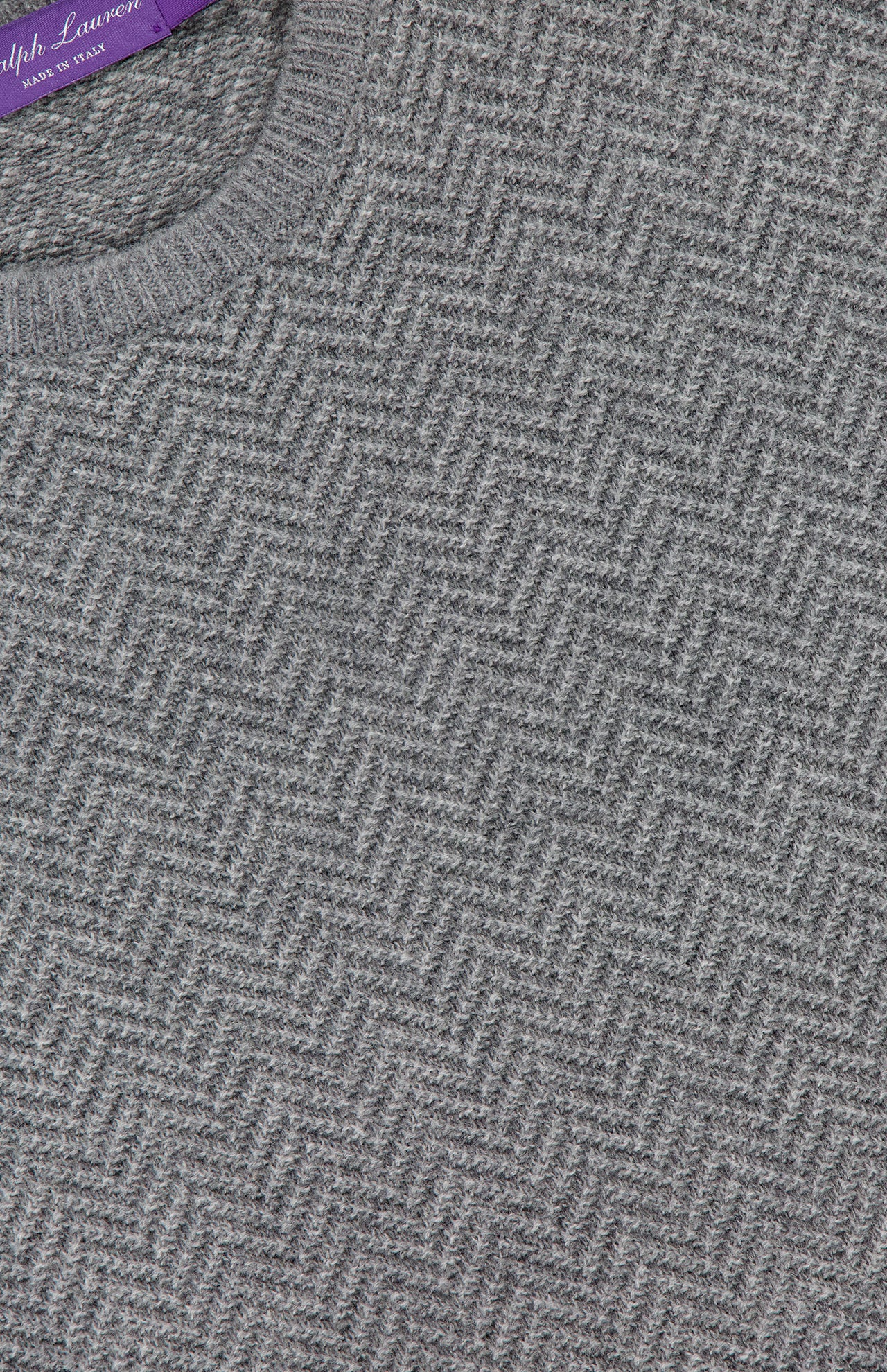 Close-up of a gray RALPH LAUREN PURPLE LABEL Herringbone Textured Crewneck Sweater, featuring a luxurious Italian-made herringbone knit and the signature purple label sewn into the neckline.