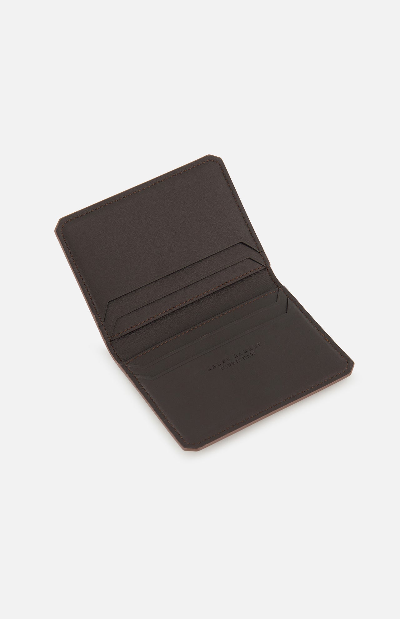 Introducing the Burnish Calf Wallet by RALPH LAUREN PURPLE LABEL—an open, dark brown luxury card case crafted from supple calfskin leather. Featuring two card slots on each side and displayed elegantly against a white background, this wallet is expertly made in Italy, embodying timeless craftsmanship and sophisticated style.