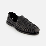 The Burnished Vacchetta Casual Loafer by RALPH LAUREN PURPLE LABEL is a black leather loafer with a woven design, closed toe, and low heel, crafted in Italy and shown on a plain white background.