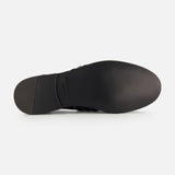 The image displays the bottom of a black Burnished Vacchetta Casual Loafer by RALPH LAUREN PURPLE LABEL, featuring a smooth sole, slight heel, embossed branding near the arch, and showcasing its Italian-made slip-on design against a white background.