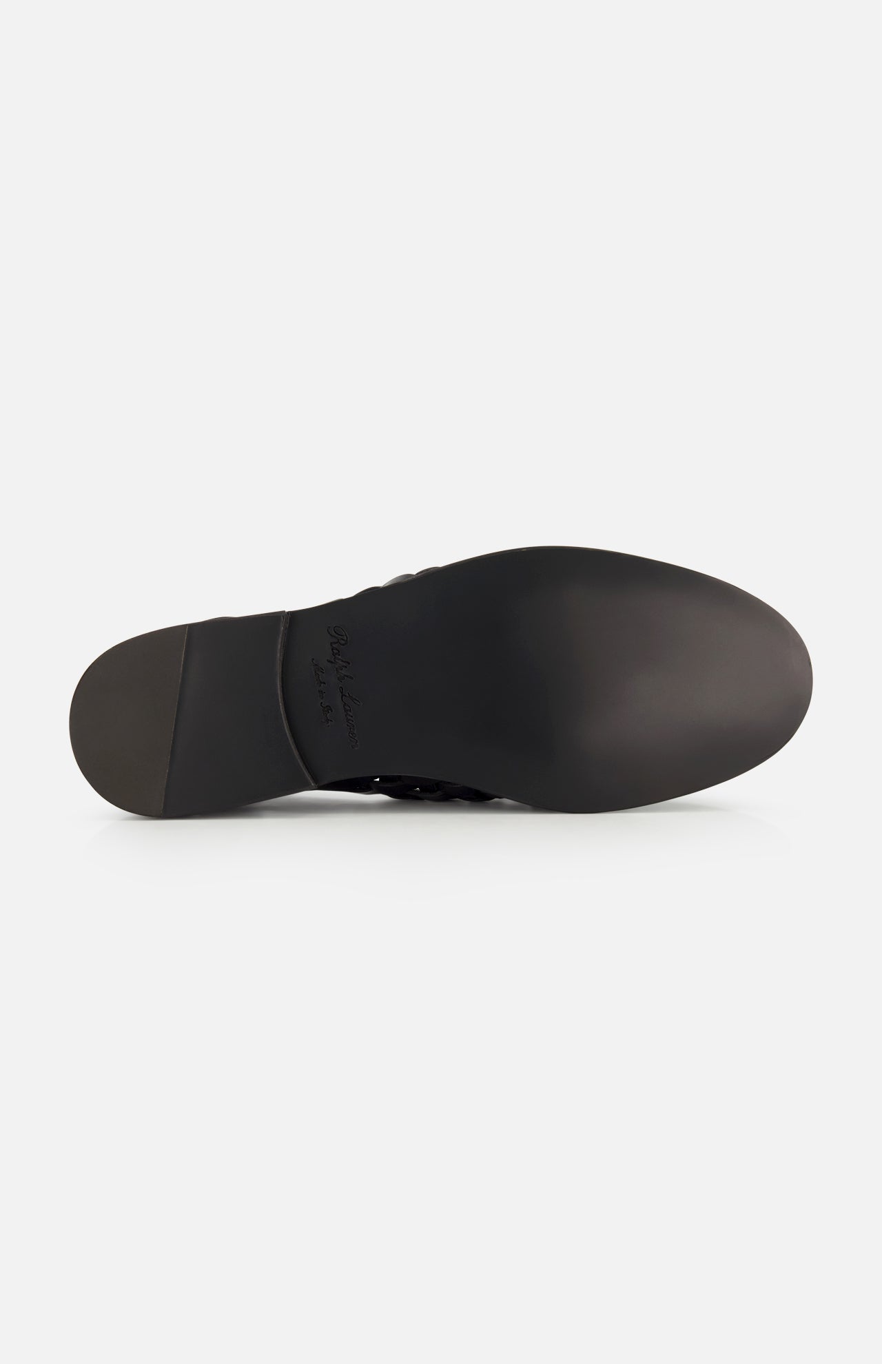 The image displays the bottom of a black Burnished Vacchetta Casual Loafer by RALPH LAUREN PURPLE LABEL, featuring a smooth sole, slight heel, embossed branding near the arch, and showcasing its Italian-made slip-on design against a white background.