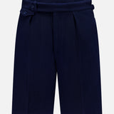 The Cashmere Herringbone Pleated Tennis Short by RALPH LAUREN PURPLE LABEL is crafted from navy blue Italian herringbone mesh fabric and features front pleats along with an adjustable side tab with buttons, shown against a plain white background.