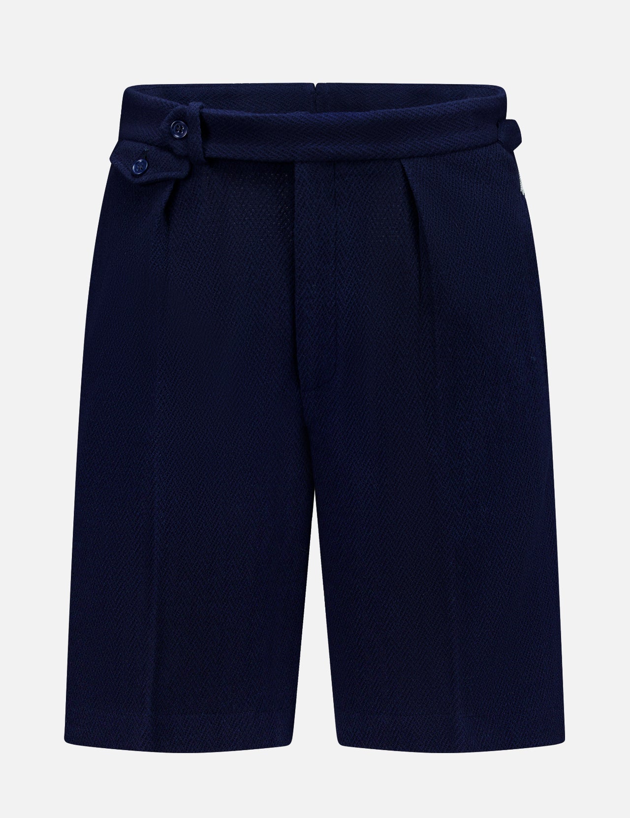The Cashmere Herringbone Pleated Tennis Short by RALPH LAUREN PURPLE LABEL is crafted from navy blue Italian herringbone mesh fabric and features front pleats along with an adjustable side tab with buttons, shown against a plain white background.