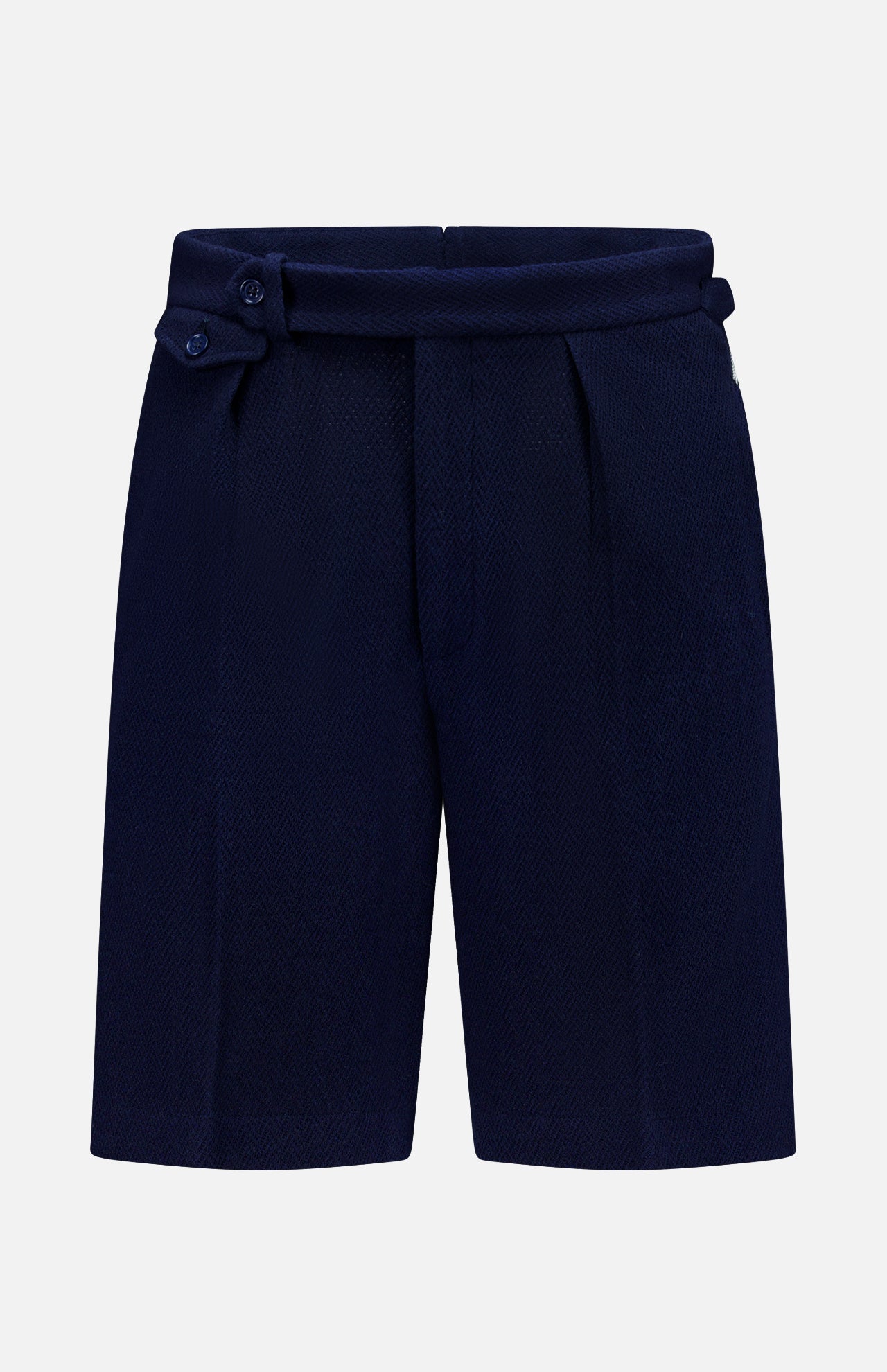 The Cashmere Herringbone Pleated Tennis Short by RALPH LAUREN PURPLE LABEL is crafted from navy blue Italian herringbone mesh fabric and features front pleats along with an adjustable side tab with buttons, shown against a plain white background.