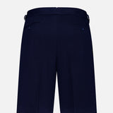 The Cashmere Herringbone Pleated Tennis Short by RALPH LAUREN PURPLE LABEL is shown from the back in navy blue, featuring two buttoned welt pockets and adjustable side tabs, displayed against a plain white background.