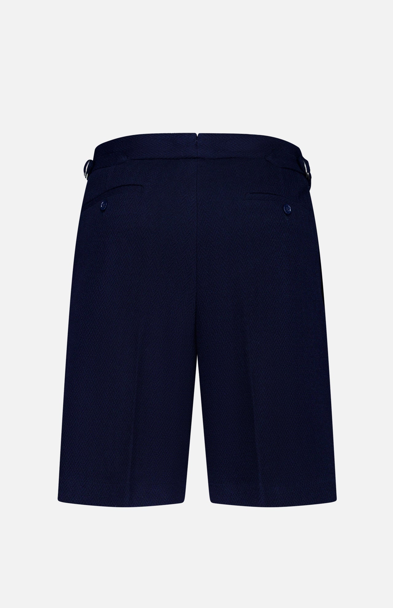 The Cashmere Herringbone Pleated Tennis Short by RALPH LAUREN PURPLE LABEL is shown from the back in navy blue, featuring two buttoned welt pockets and adjustable side tabs, displayed against a plain white background.
