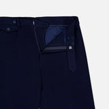 The Cashmere Herringbone Pleated Tennis Short by RALPH LAUREN PURPLE LABEL is shown in navy blue Italian tailoring with the waistband and fly open to reveal the interior lining and button details, set against a plain white background.