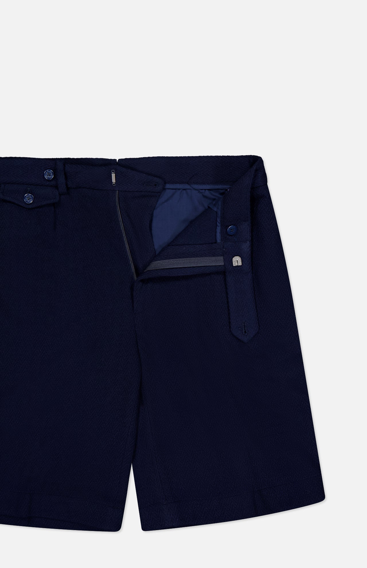 The Cashmere Herringbone Pleated Tennis Short by RALPH LAUREN PURPLE LABEL is shown in navy blue Italian tailoring with the waistband and fly open to reveal the interior lining and button details, set against a plain white background.