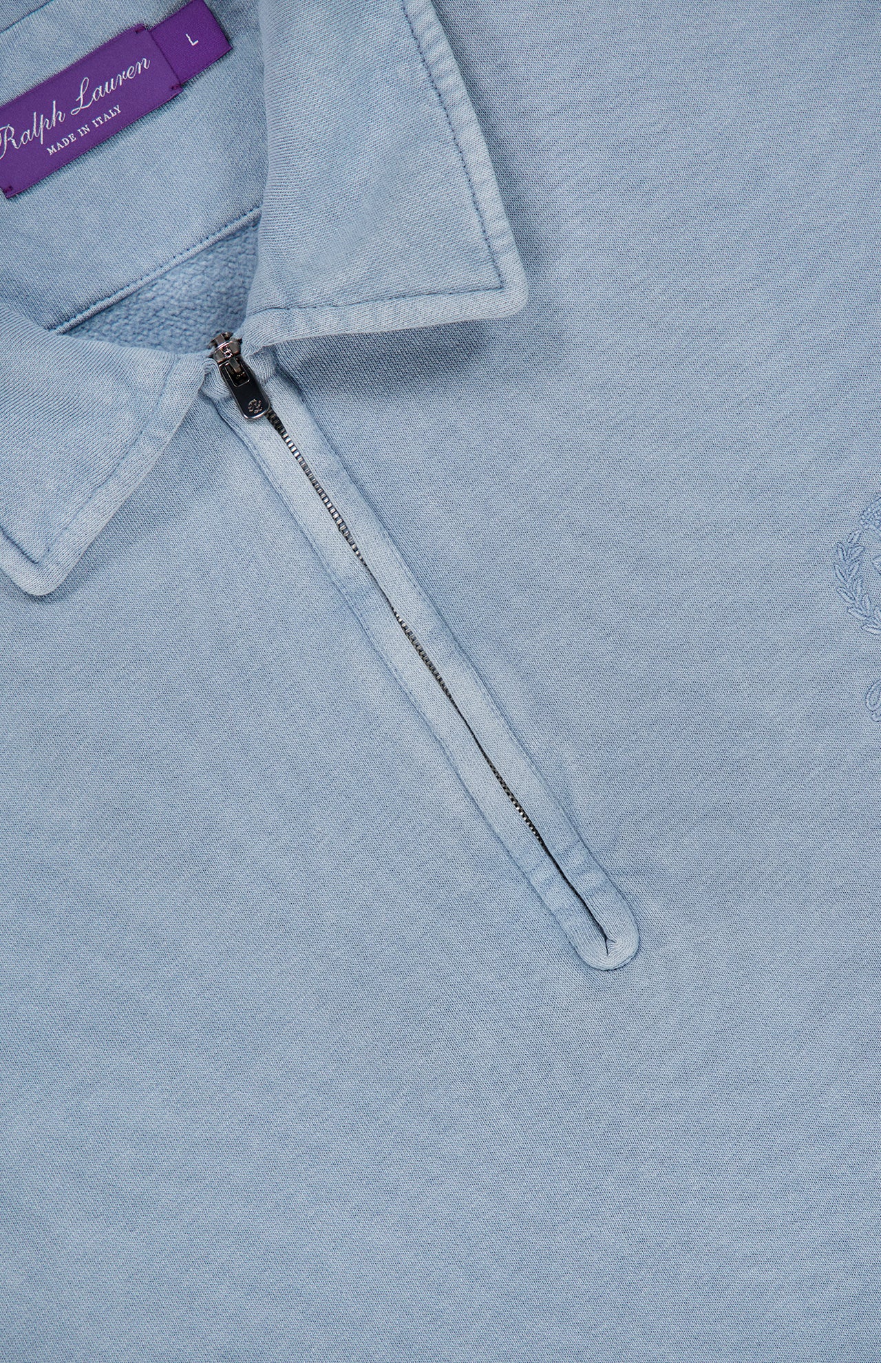 A pale blue Cashmere Long Sleeve Quarter Zip Polo Sweatshirt by RALPH LAUREN PURPLE LABEL, featuring a collar, partial front zipper, and a distinctive purple “Ralph Lauren Made in Italy” tag. This men’s casual sweatshirt offers refined comfort and effortless style with its subtle embroidered design on the right side.