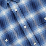A close-up of the Cooper Cotton Plaid Sport Shirt highlights its blue and white plaid button-up design with white buttons and a collar. The shirt features a purple RALPH LAUREN PURPLE LABEL at the top left, emphasizing this classic sport shirt from Ralph Lauren’s premium collection.