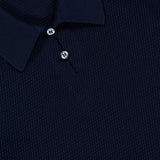 Close-up of a dark navy textured Cotton Short Sleeve Polo Pullover Sweater with two buttons and a collar, reflecting the refined craftsmanship characteristic of RALPH LAUREN PURPLE LABEL. A purple label inside the collar reads "Ralph Lauren Made in Italy" in white text, highlighting its luxurious origins.