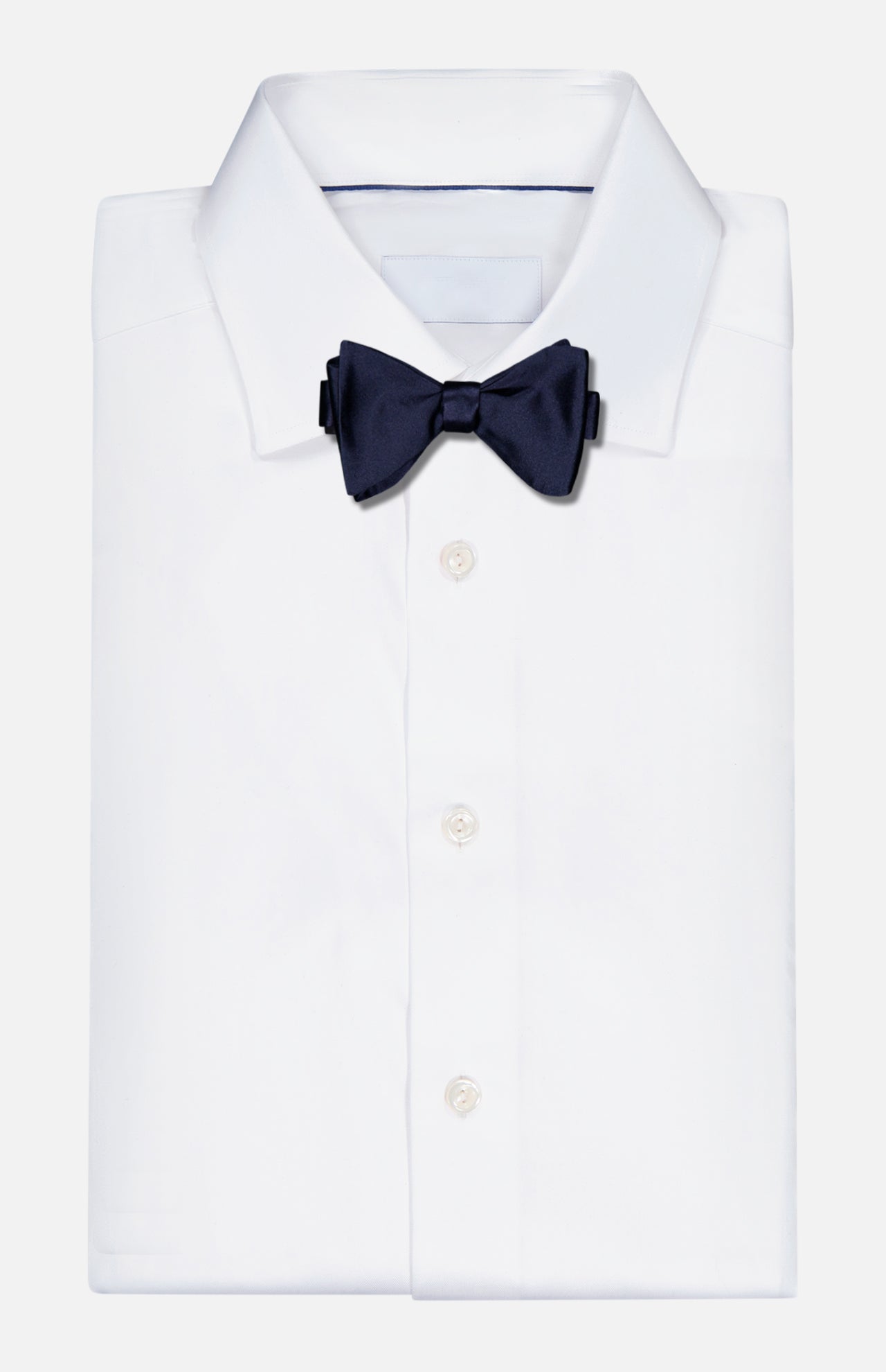 A Formal Satin Bow Tie by RALPH LAUREN PURPLE LABEL in dark navy is elegantly attached to a neatly folded white dress shirt, set against a plain light background.