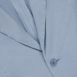Close-up of the Garment Dyed Cotton Single Breasted Sportcoat by RALPH LAUREN PURPLE LABEL in light blue, featuring hand-tailored Italian craftsmanship with neatly pressed fabric, detailed lapels, buttons, and a pocket.