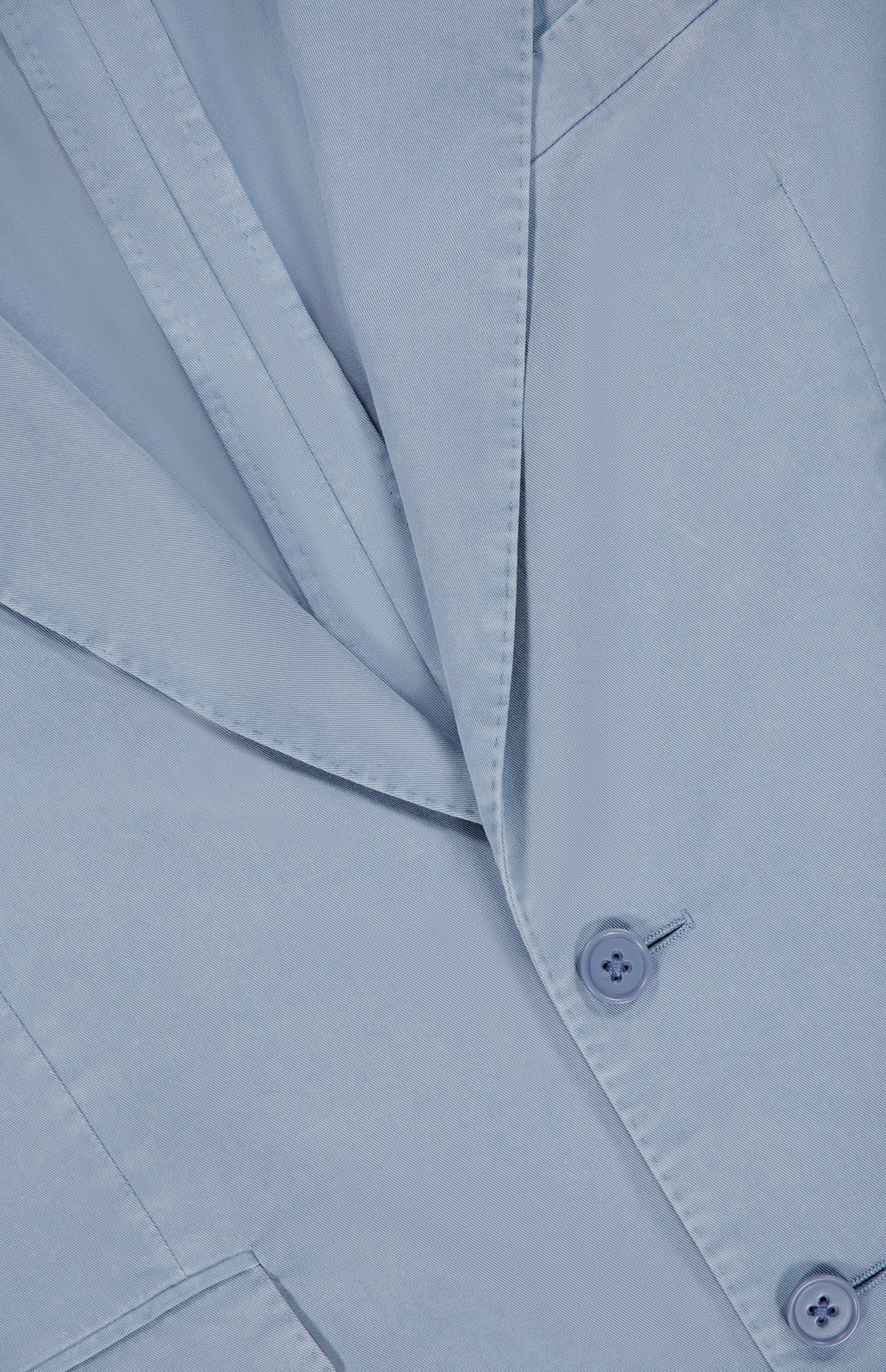 Close-up of the Garment Dyed Cotton Single Breasted Sportcoat by RALPH LAUREN PURPLE LABEL in light blue, featuring hand-tailored Italian craftsmanship with neatly pressed fabric, detailed lapels, buttons, and a pocket.