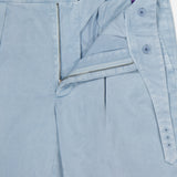 The Garment Dyed Cotton Trouser Pant by RALPH LAUREN PURPLE LABEL is shown in light blue with the waistband, zipper, and button fly open to reveal interior details and button closures. Visible stitching highlights the meticulous construction and modern style of these smooth, garment-dyed pants.