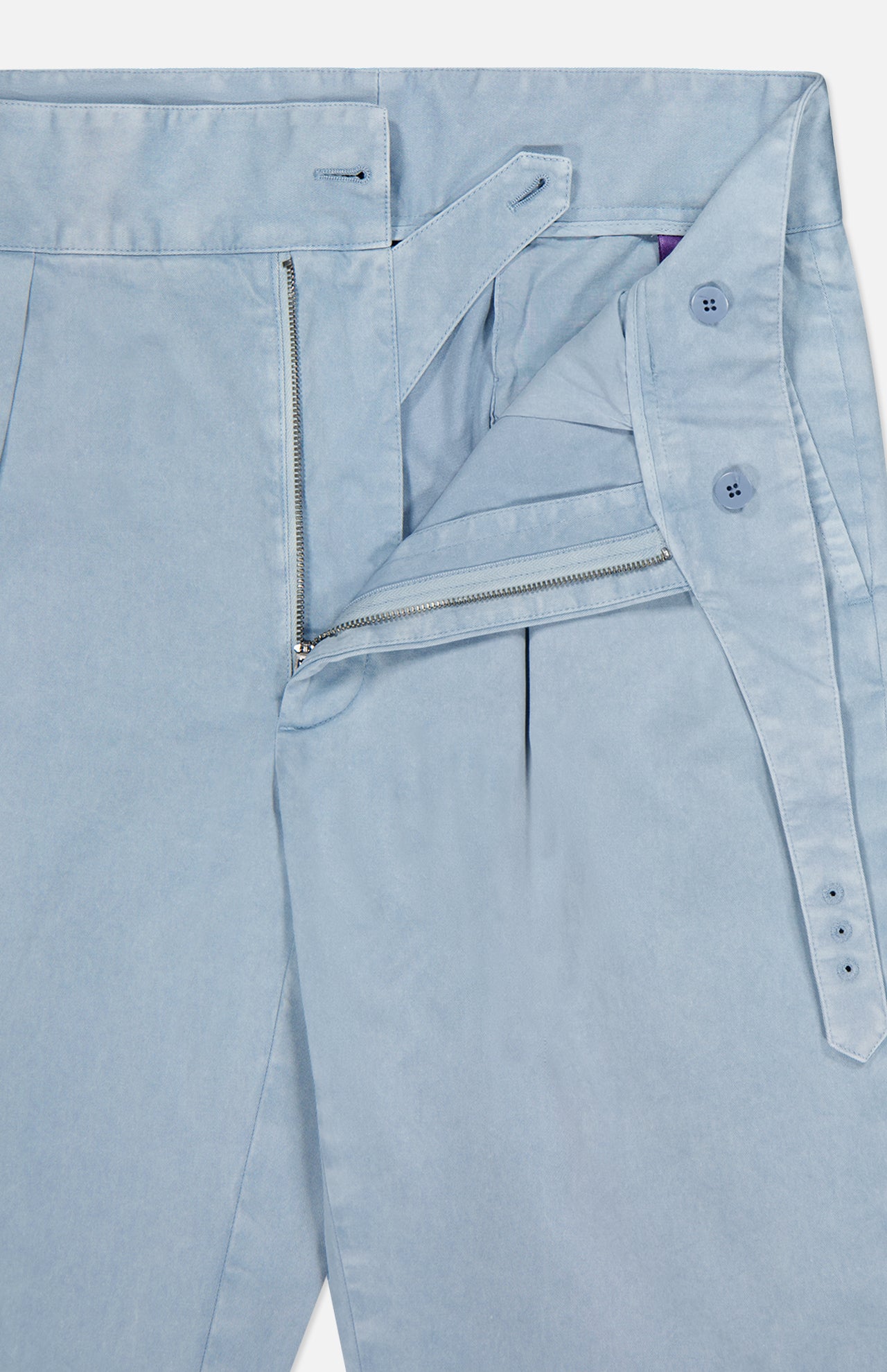 The Garment Dyed Cotton Trouser Pant by RALPH LAUREN PURPLE LABEL is shown in light blue with the waistband, zipper, and button fly open to reveal interior details and button closures. Visible stitching highlights the meticulous construction and modern style of these smooth, garment-dyed pants.