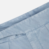 Close-up of a light blue pleated fabric from the RALPH LAUREN PURPLE LABEL Garment Dyed Cotton Trouser Pant, featuring the waistband and neatly stitched seams against a white background.