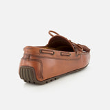The Harold Hand Burnished Tassle Loafer by RALPH LAUREN PURPLE LABEL is a brown leather shoe crafted from premium French box calfskin, showcasing visible stitching, a rubber sole, and tassel lace accents, displayed from the rear side against a white background.