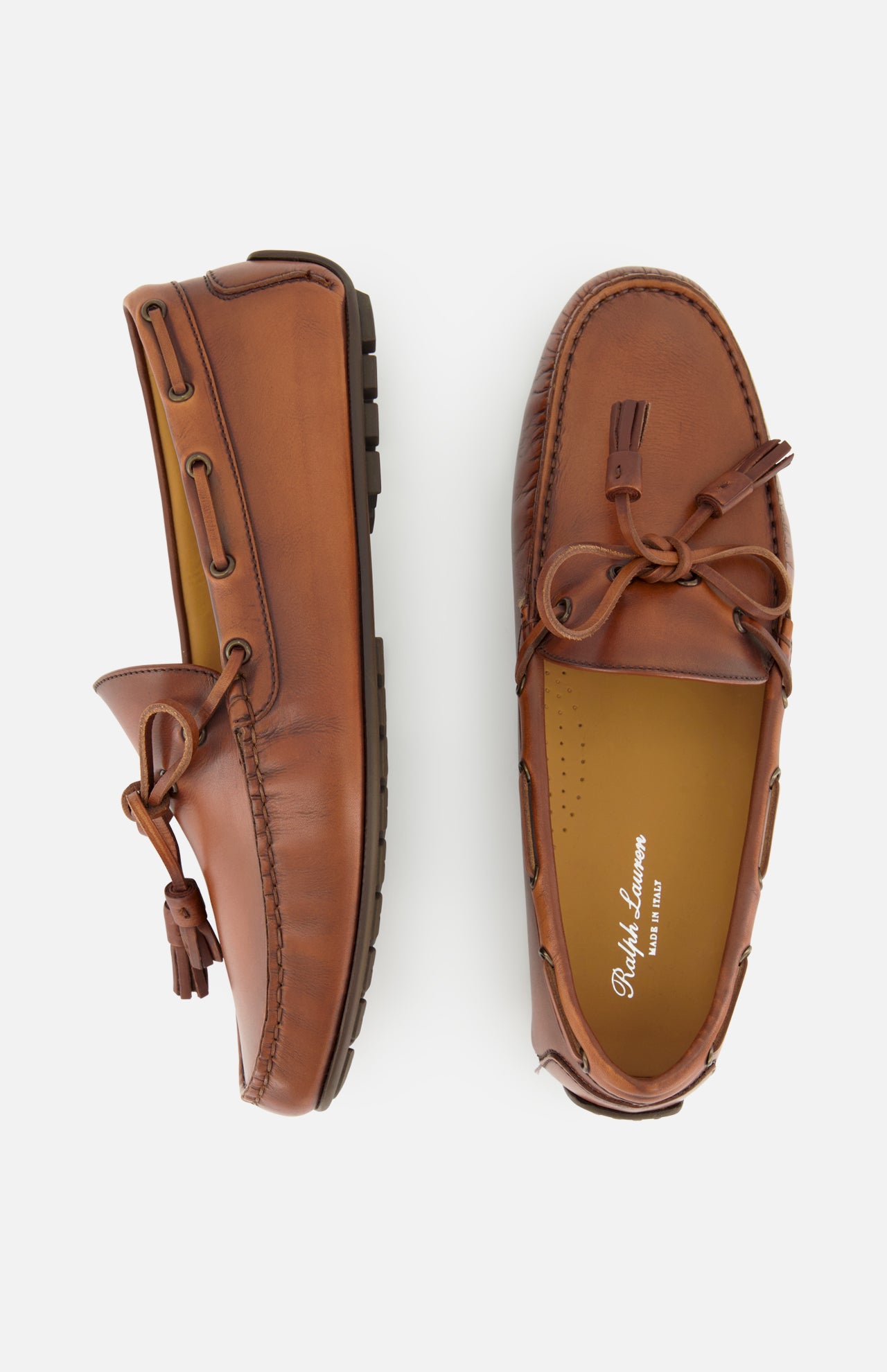 Presenting the Harold Hand Burnished Tassle Loafer from RALPH LAUREN PURPLE LABEL: a pair of brown leather loafers crafted from premium French box calfskin, featuring hand-applied burnishing, visible stitching, and refined rubber sole details. Shown from above and the side, these timeless slip-ons with elegant tassels combine sophistication and comfort for any occasion.