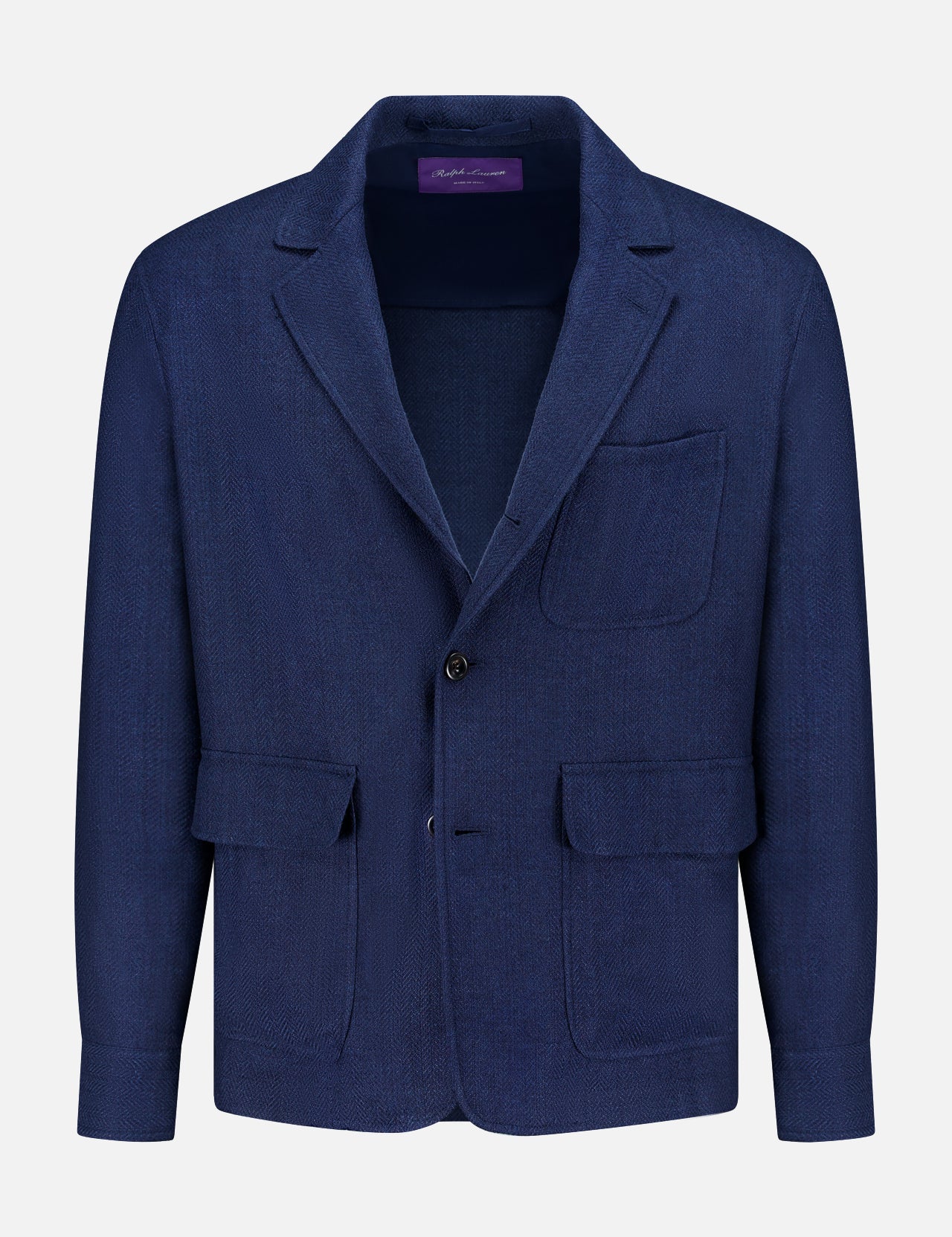 The Herringbone Single Breasted Sportcoat from RALPH LAUREN PURPLE LABEL is an Italian hand-tailored jacket in navy blue, featuring a notched lapel, one chest pocket, two front flap pockets, and a two-button front closure. The sportcoat is expertly crafted and displayed against a white background.