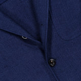 Close-up of the Herringbone Single Breasted Sportcoat by RALPH LAUREN PURPLE LABEL, featuring a blue textured fabric with distinctive stitching, buttons, and a front pocket. The image emphasizes the refined herringbone weave and deep indigo hue, capturing the handcrafted elegance for which Ralph Lauren Purple Label is renowned.