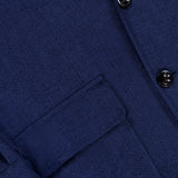 Close-up of the Herringbone Single Breasted Sportcoat by RALPH LAUREN PURPLE LABEL in dark blue, featuring a herringbone fabric, a flap pocket, sleeve cuff with button detail, and part of the front placket with two black buttons.