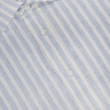 A close-up of the Linen Stripe Sport Shirt by RALPH LAUREN PURPLE LABEL, featuring light blue and white vertical stripes in lightweight, semi-sheer dobby linen, finished with elegant Mother of Pearl buttons.