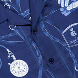 Close-up of a blue RALPH LAUREN PURPLE LABEL Printed Silk Short Sleeve Sport Shirt, made in Italy, adorned with illustrations of gloves, a stopwatch, a perfume bottle, and straps, and finished with black buttons down the front.