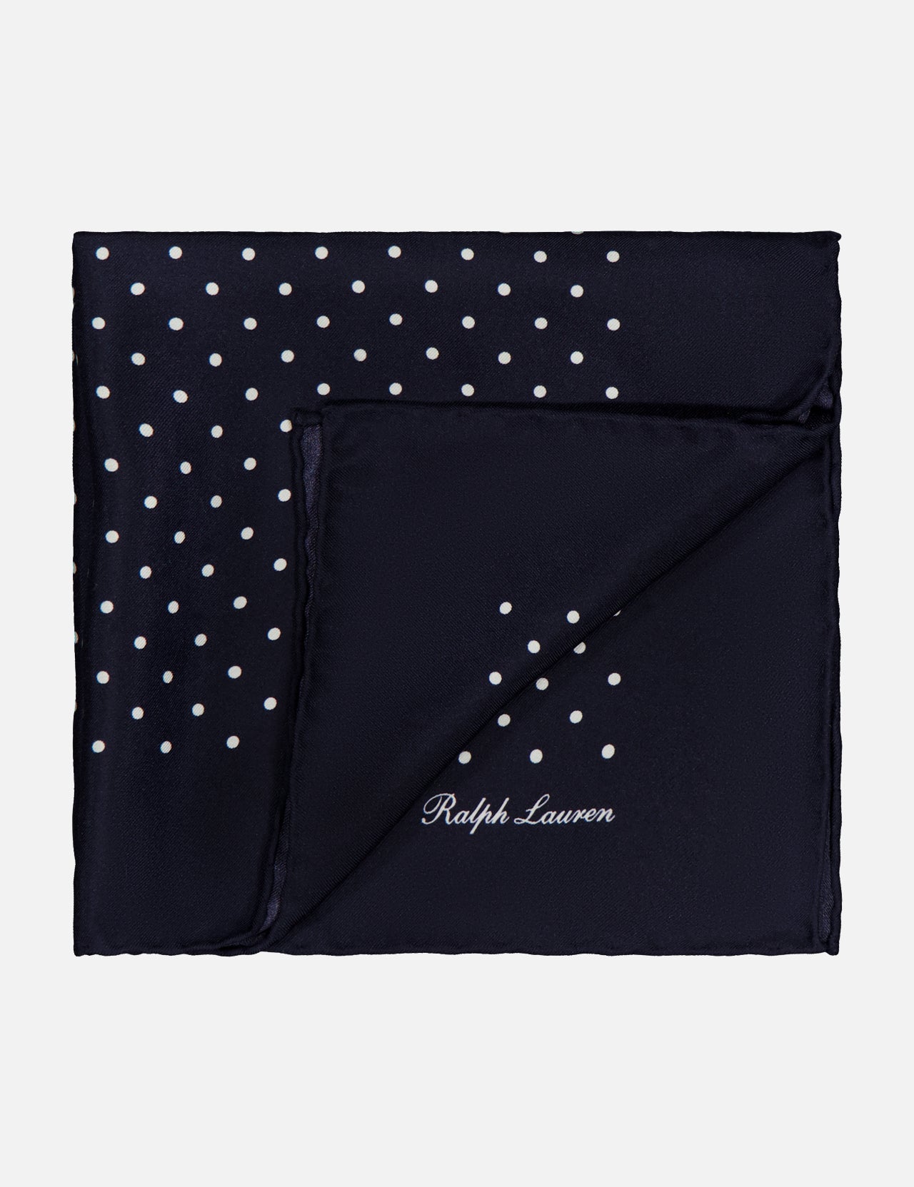 The RALPH LAUREN PURPLE LABEL Silk Foulard Dot Pocket Square is crafted in Italy in navy blue silk, featuring white polka dots in one corner and the Ralph Lauren logo embroidered in white on the opposite corner.