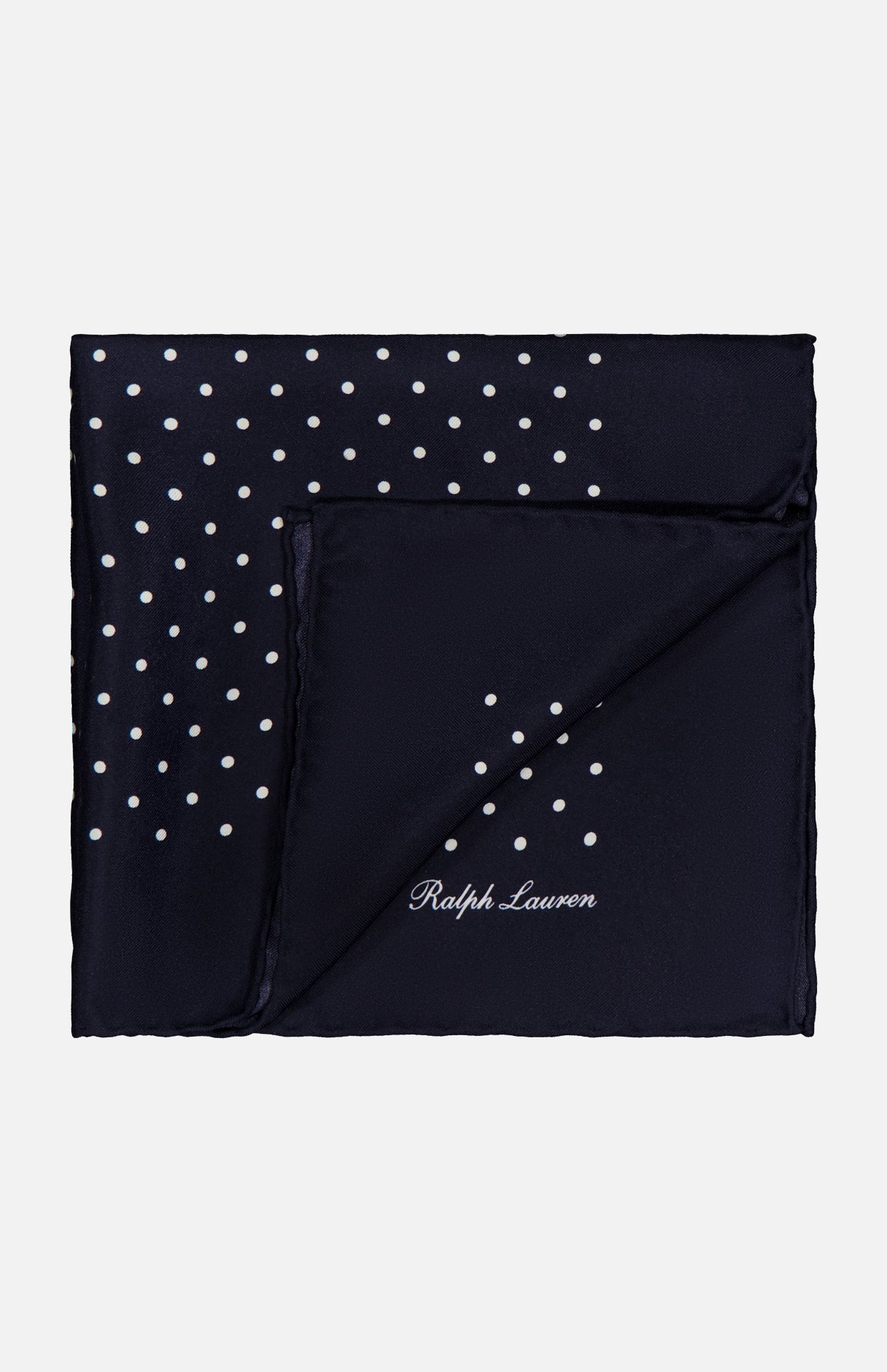 The RALPH LAUREN PURPLE LABEL Silk Foulard Dot Pocket Square is crafted in Italy in navy blue silk, featuring white polka dots in one corner and the Ralph Lauren logo embroidered in white on the opposite corner.