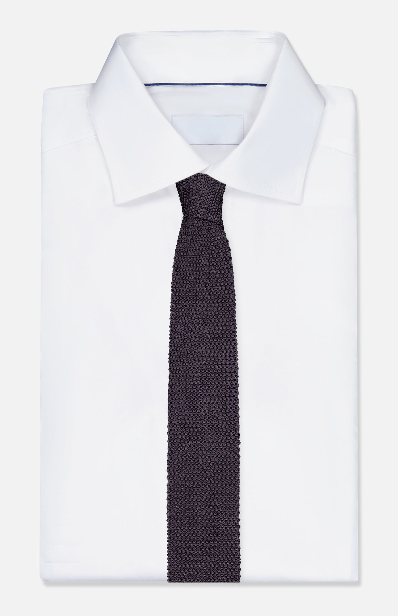 A neatly folded white dress shirt with a pointed collar is paired with the RALPH LAUREN PURPLE LABEL Superknit Silk Tie, crafted in Italy, and displayed on a plain white background.