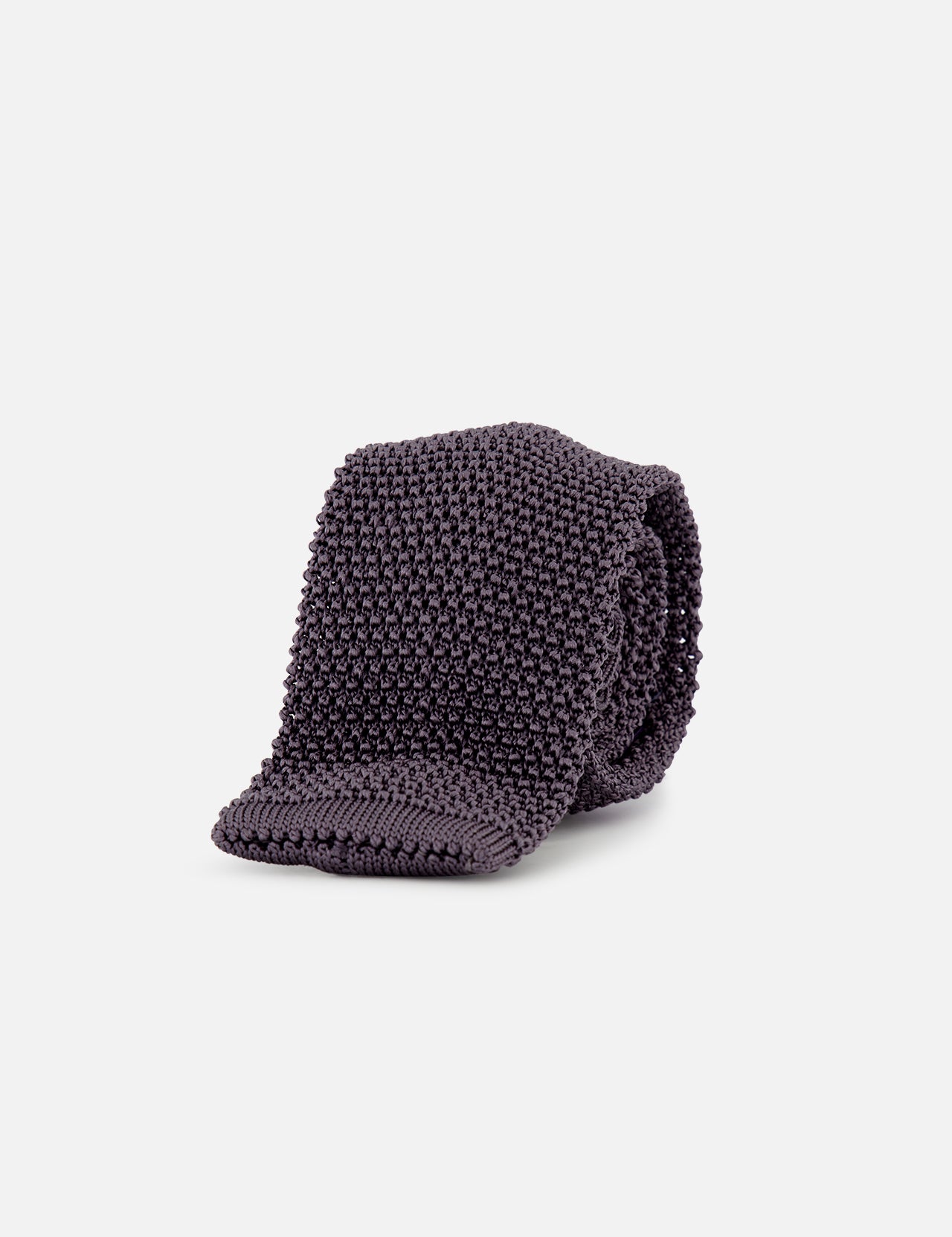 The Superknit Silk Tie by RALPH LAUREN PURPLE LABEL, crafted in Italy in a dark grey knit, is rolled up and showcased against a plain white background.
