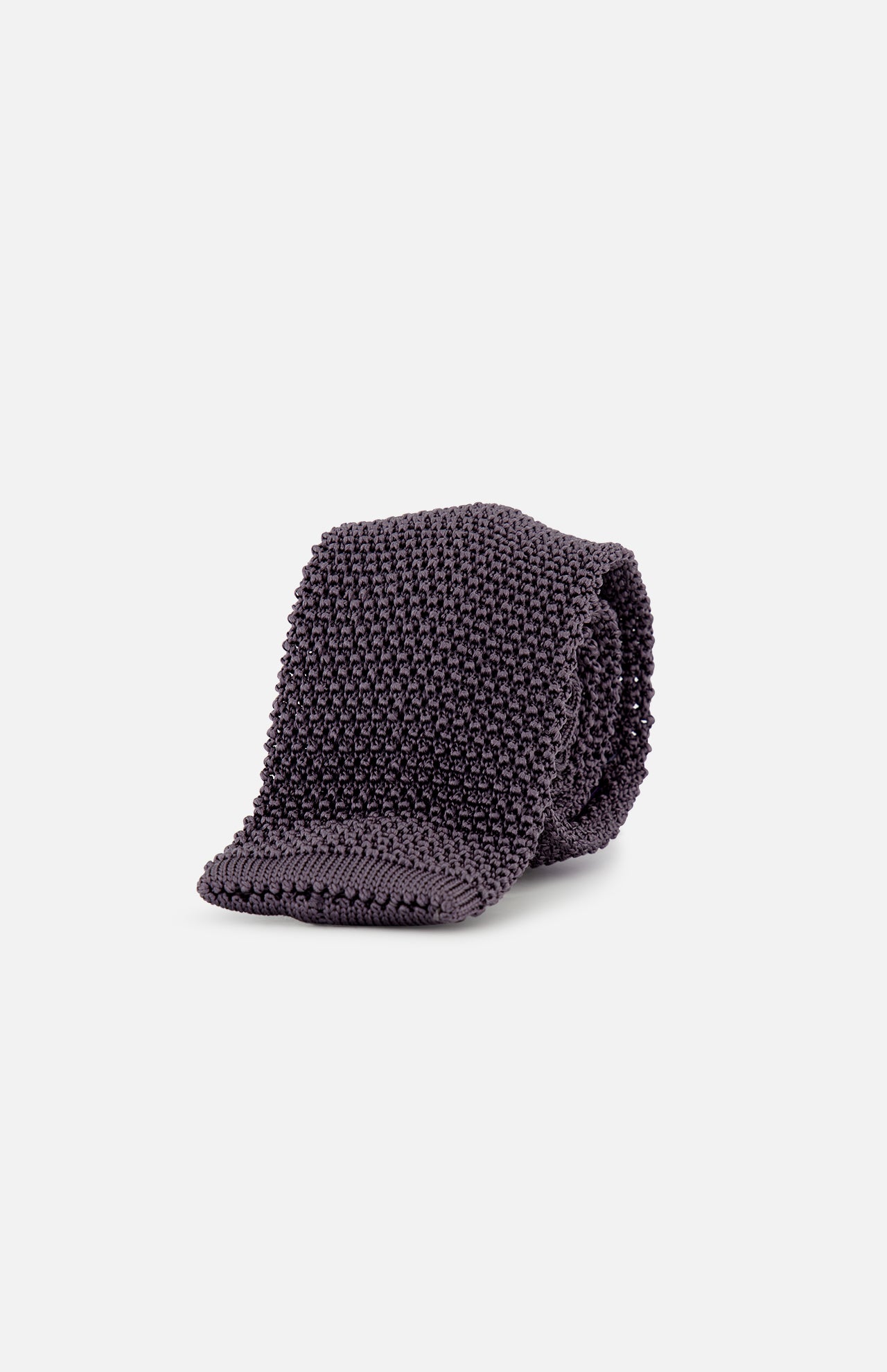 The Superknit Silk Tie by RALPH LAUREN PURPLE LABEL, crafted in Italy in a dark grey knit, is rolled up and showcased against a plain white background.