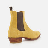 The RALPH LAUREN PURPLE LABEL Western Suede Mid Cut Boot features a tan suede upper with brown elastic side panels, a pull tab, and a stacked wooden heel, all displayed against a white background—these classic boots embody timeless style, seamlessly blending the refined appeal of tan footwear with understated western-inspired details.