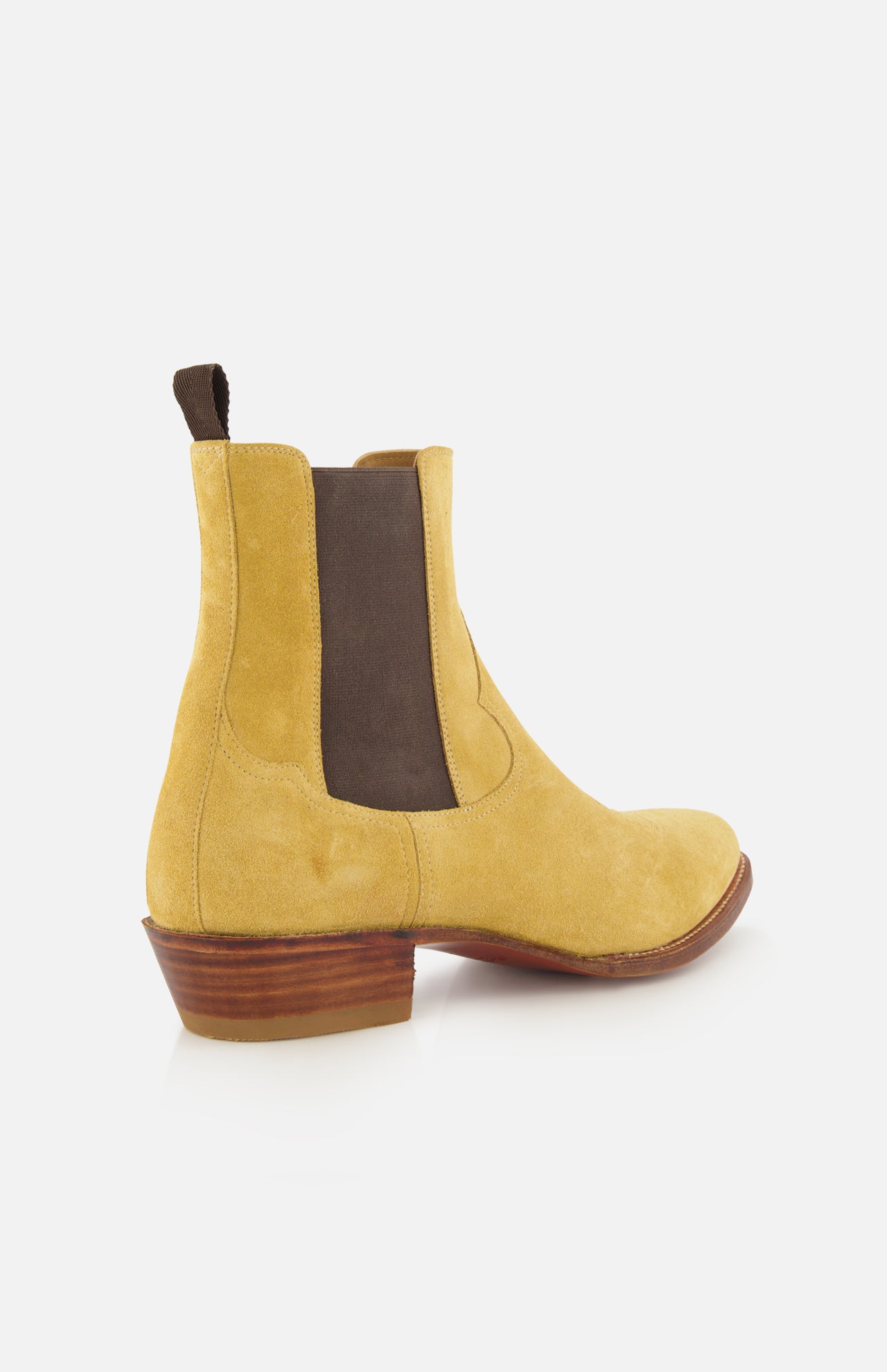The RALPH LAUREN PURPLE LABEL Western Suede Mid Cut Boot features a tan suede upper with brown elastic side panels, a pull tab, and a stacked wooden heel, all displayed against a white background—these classic boots embody timeless style, seamlessly blending the refined appeal of tan footwear with understated western-inspired details.