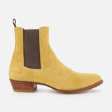 The RALPH LAUREN PURPLE LABEL Western Suede Mid Cut Boot, shown from the side on a white background, is a tan suede Chelsea-inspired design featuring classic western boot elements, including a brown elastic side panel, back pull tab, low stacked wooden heel, and brown sole.