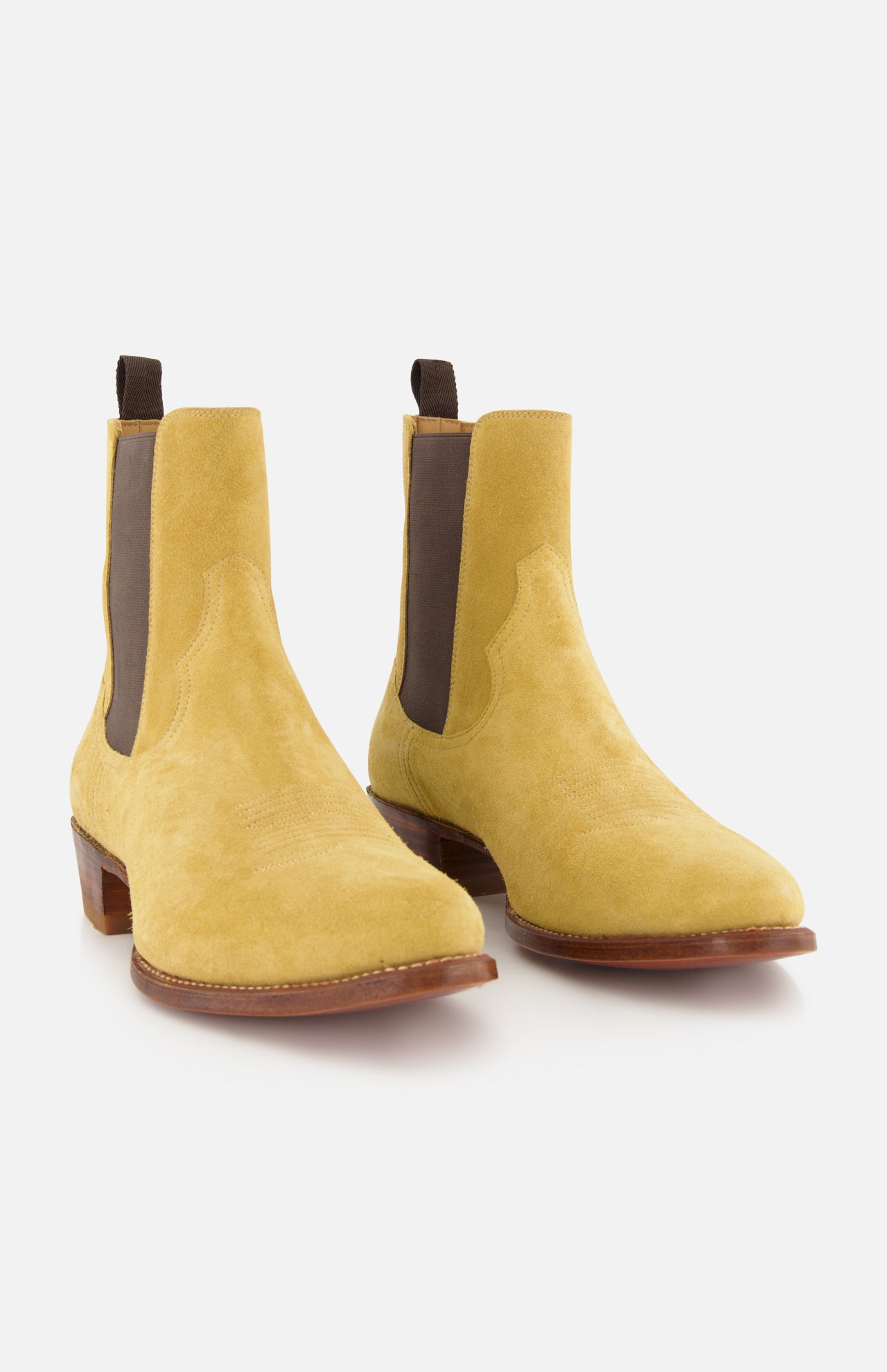 The RALPH LAUREN PURPLE LABEL Western Suede Mid Cut Boot is styled in the spirit of western boots, featuring yellow suede construction, brown elastic side panels, and wooden soles, positioned on a white background.