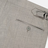 Close-up view of the RALPH LAUREN PURPLE LABEL Wool Flannel Pleated Trouser in light gray, featuring a back pocket with a button and a side adjuster with a metal buckle at the waistband; hand-tailored in Italy and shown against a plain white background.