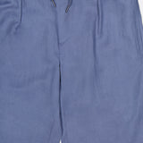 The Ralph Lauren Purple Label Silk Linen Dorset Flat Front Trouser in light blue features a soft, unpatterned fabric, an elastic waistband with drawstring tie, and is shown from waist to mid-thigh.