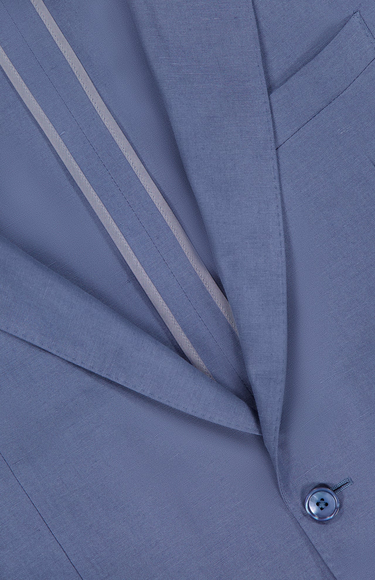 Close-up of the Ralph Lauren Purple Label Silk Linen Single Breasted Sportcoat in light blue, highlighting the lapel, chest pocket, single button, and inner lining with two beige stripes.