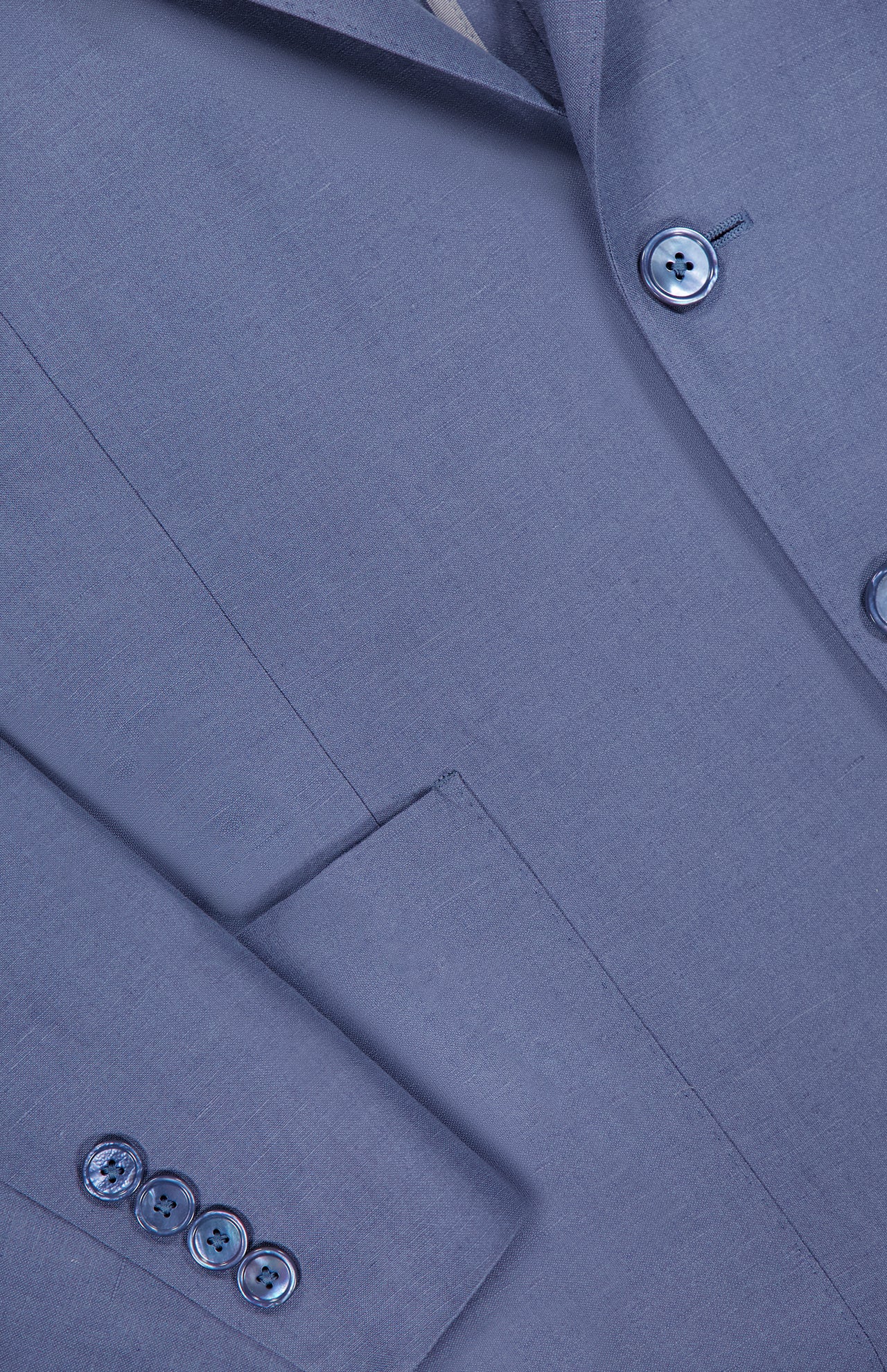 A close-up of the Ralph Lauren Purple Label Silk Linen Single Breasted Sportcoat shows a matching blue front pocket, sleeve with four buttons, and two front buttons.