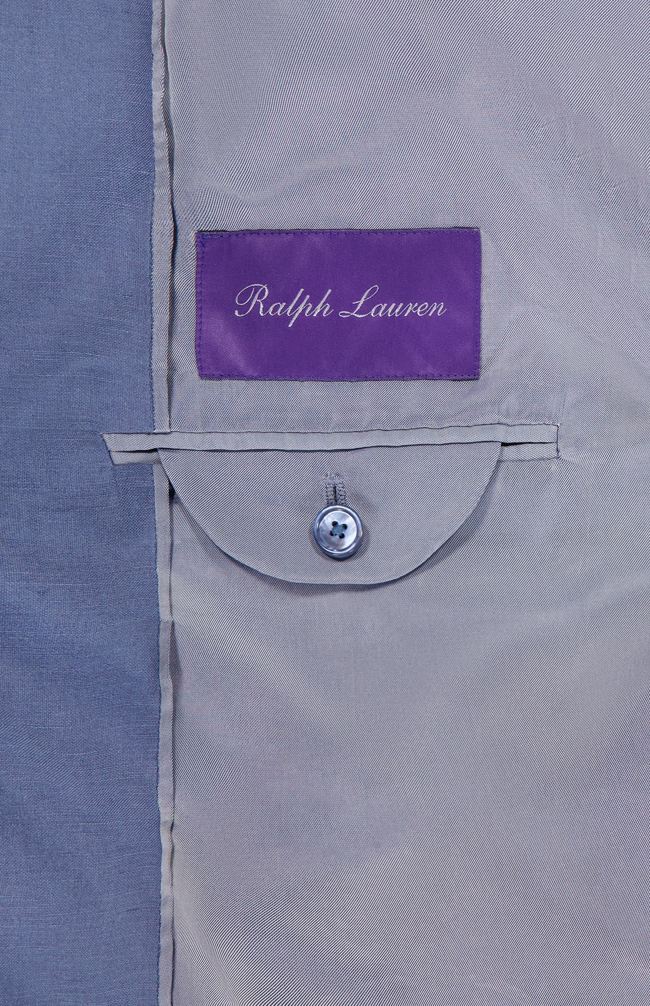 Close-up of the inside of a Silk Linen Single Breasted Sportcoat featuring a Ralph Lauren Purple Label above a small buttoned pocket on a light gray lining.