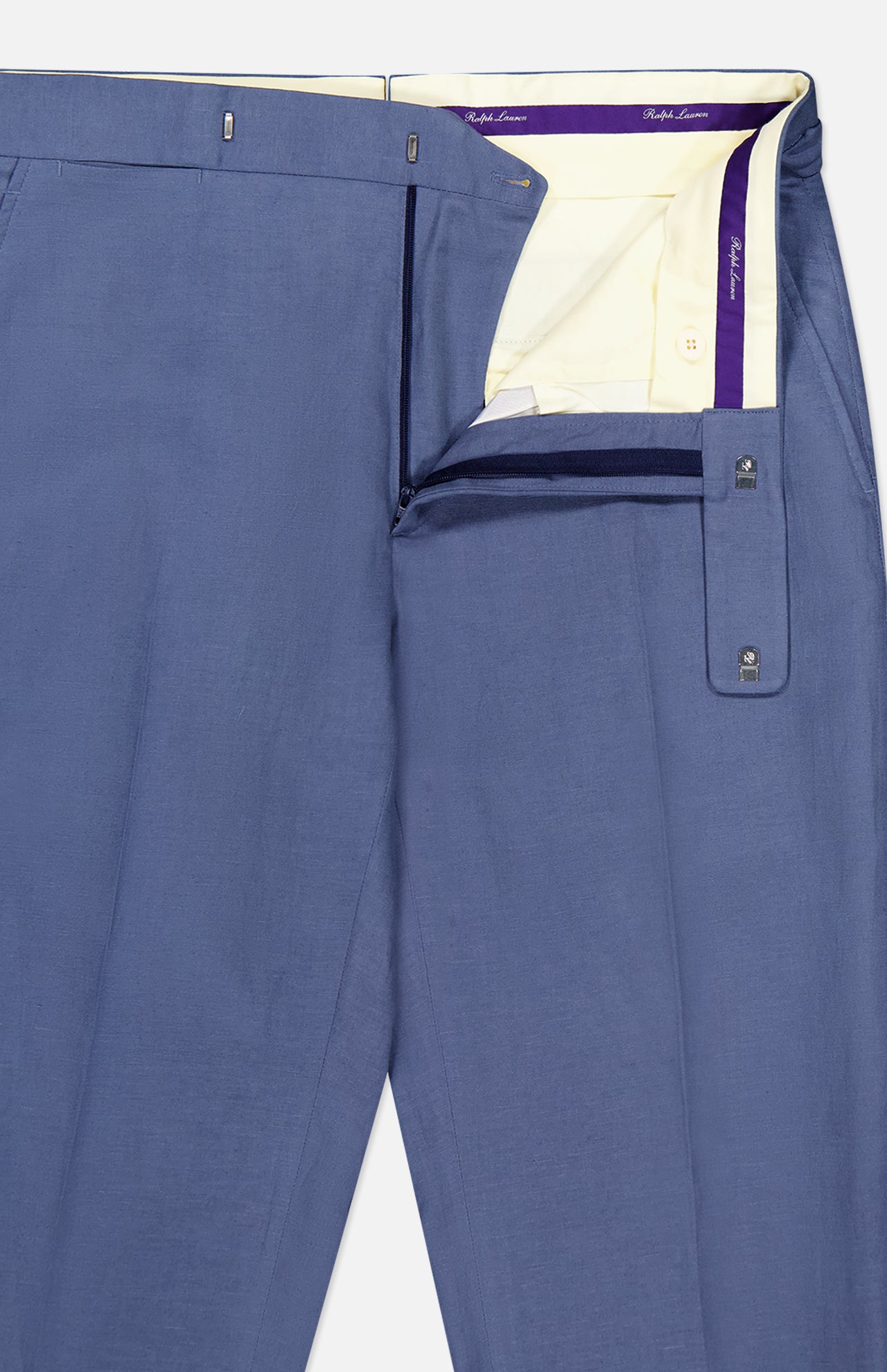 Ralph Lauren Purple Label Silk Linen Trouser in blue, partially unzipped and unbuttoned to reveal the cream inner waistband with purple trim and inner buttons, neatly laid flat on a white background.