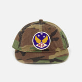 The RALPH LAUREN RRL Cotton Ripstop Printed Camo Ball Hat features a vintage look with a round patch of yellow birds, three stars, "RRL" in red on blue and white, and an adjustable back strap for the perfect fit.