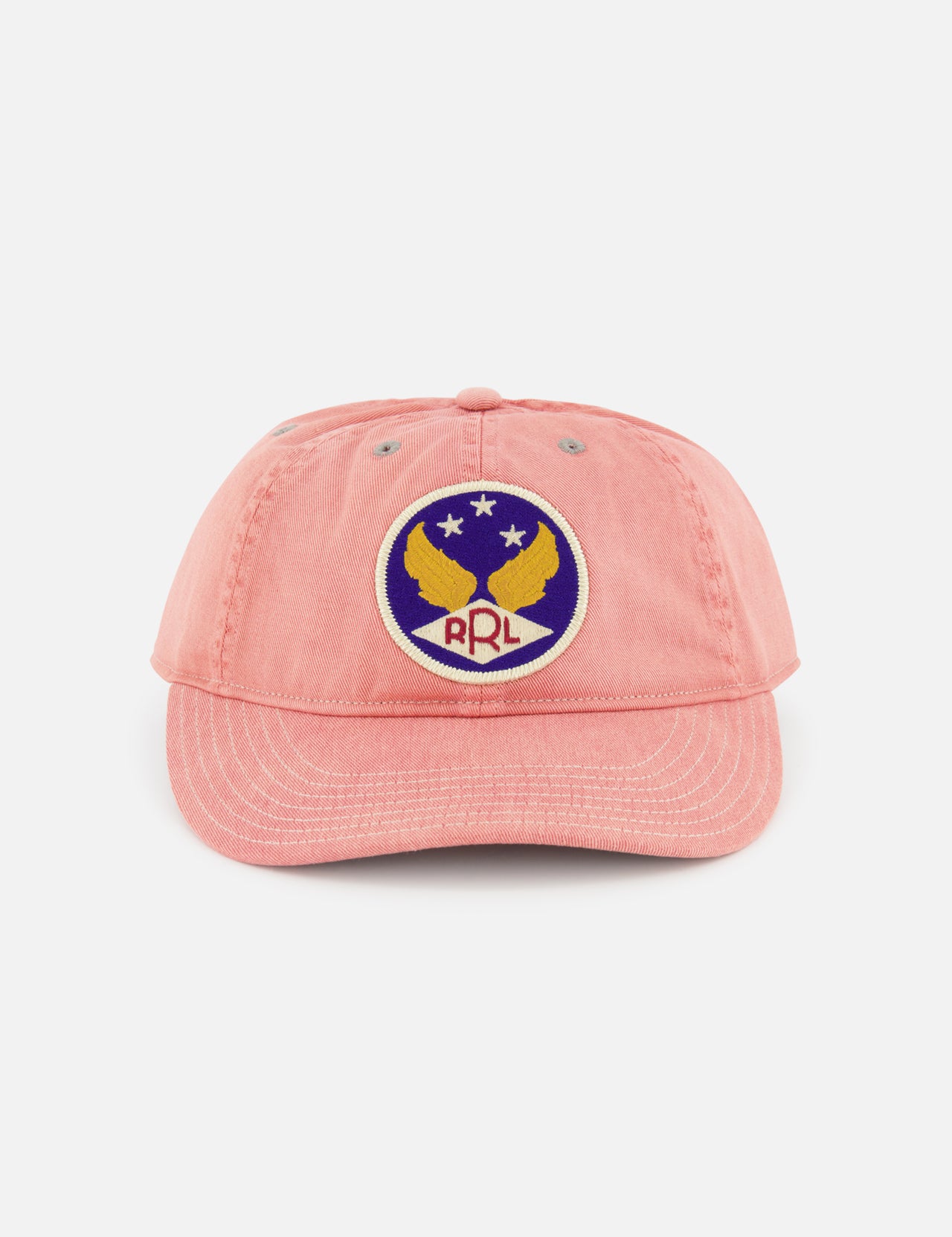 The Cotton Twill Faded Ball Hat by RALPH LAUREN RRL features soft pink cotton twill, a curved brim, and an embroidered patch with two yellow eagles, a star, and “RRL” on a blue and white circular background for vintage style.