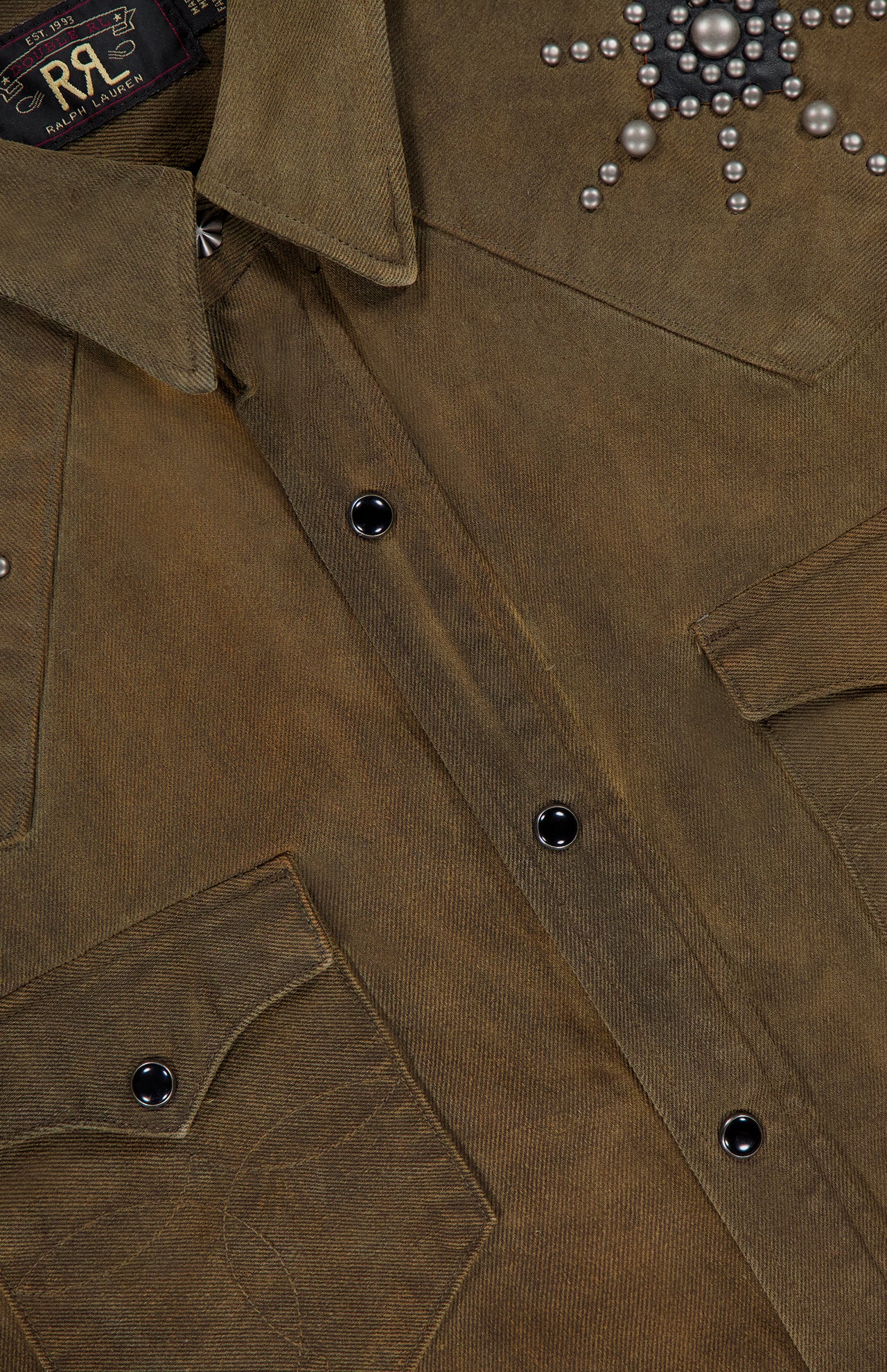 Close-up of the Denim Buffalo Western Shirt by RALPH LAUREN RRL, featuring black snap buttons, two chest pockets, and a metal stud starburst detail near the shoulder.